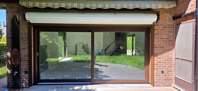 Coffre de volet roulant en aluminium fixé en applique sur la façade, au-dessus d'une baie vitrée coulissante