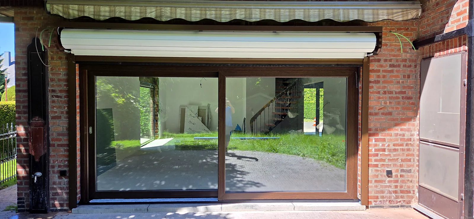 Baie coulissante avec volet roulant intégré au-dessus, cadre effet bois posé dans une façade en briques